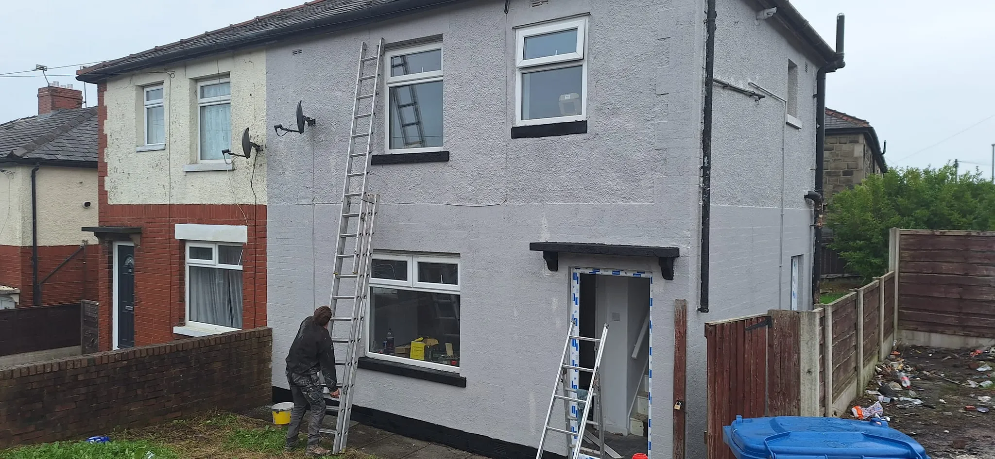 a man standing on a ladder in front of a house