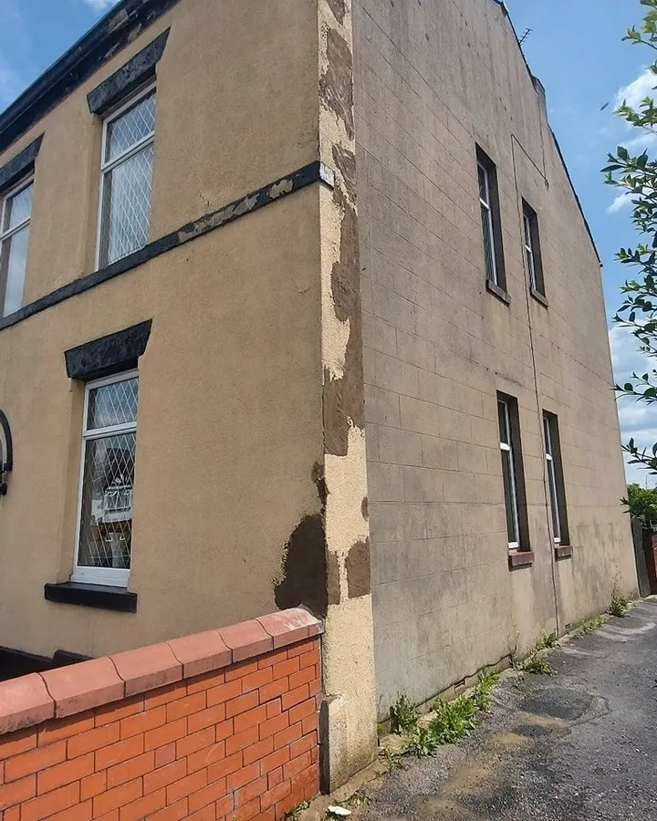 a building with a brick wall and a clock on the side of it