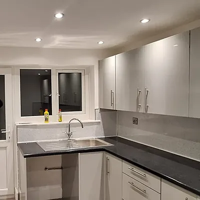 A kitchen with white cabinets and black counter tops.