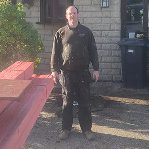 A man standing in front of a brick building.